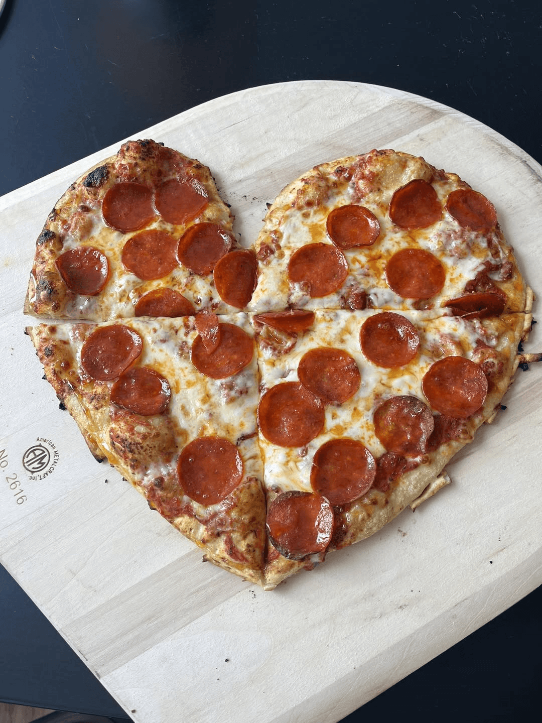 Heart-shaped pepperoni pizza on a wooden board