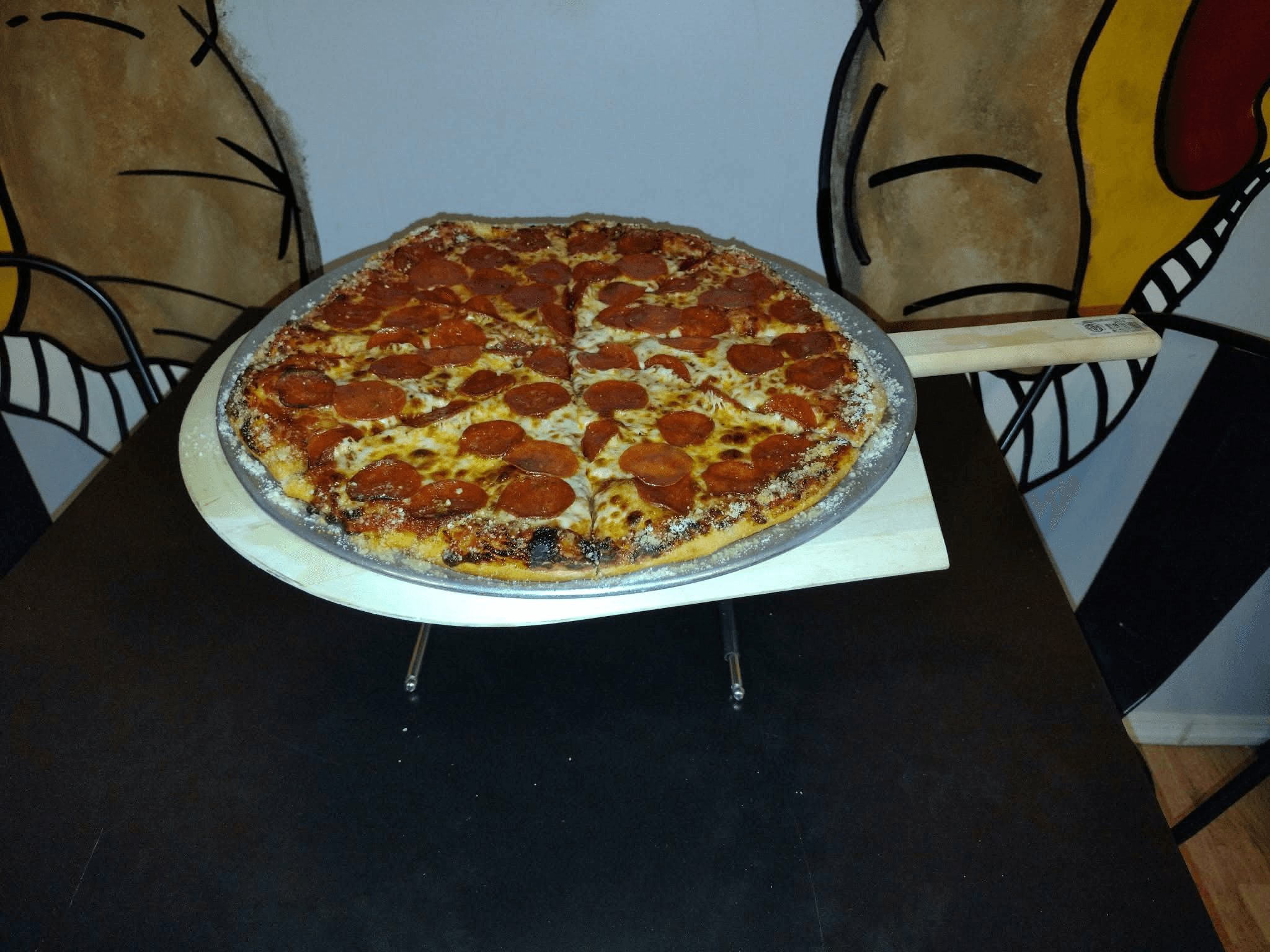 Classic pepperoni pizza inside Cell Block Pizza with cartoon murals